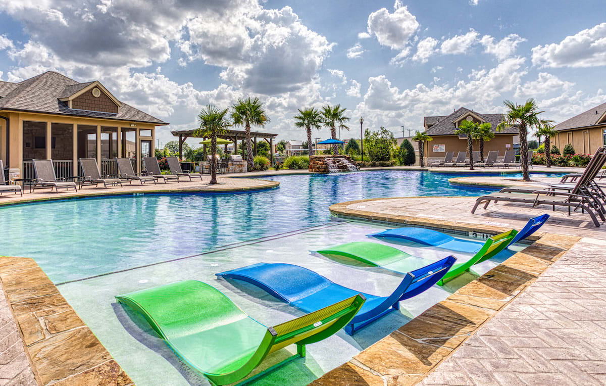 lounge chairs in pool at apartment building complex